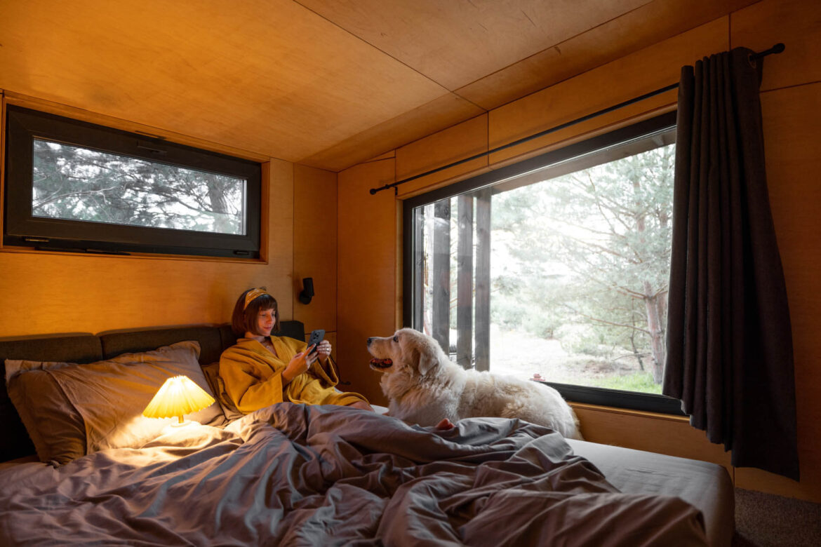 Frau mit Hund in kleinem Schlafzimmer eines Tiny House in Holland