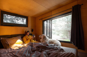 Frau mit Hund in kleinem Schlafzimmer eines Tiny House in Holland