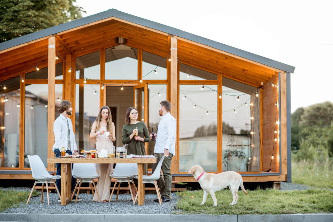 Freunde mit Getränken auf dem Hinterhof eines Tiny Houses in Holland, welches 100qm groß ist.