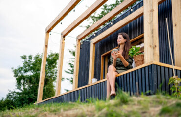 Junge Frau mit Smartphone im Freien, Wochenende im Tiny House im Saarland