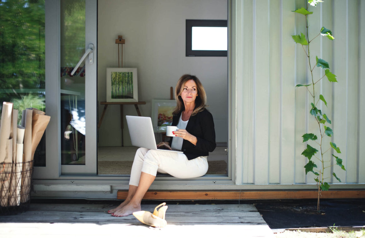 Reife Frau arbeitet auf der Terasse ihres Tiny House in Hamburg