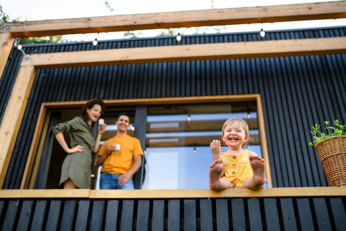 Tiefblick auf Familie aus 4 Personen mit kleiner Tochter auf der Terasse eines Tiny House