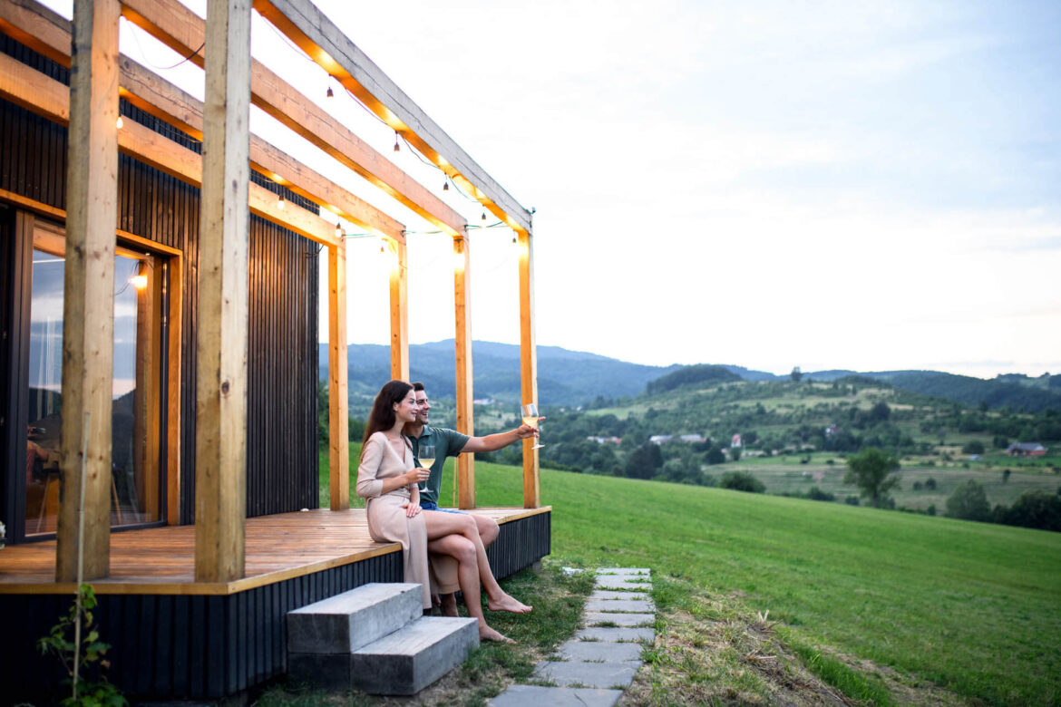 junges Paar mit Wein im Freien auf der Terasse eines Tiny House in Bayern auf einen Privatgrundstück