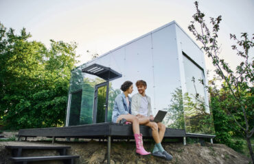 junges multiethnisches Paar sitzt auf Veranda eines Tiny House in Östereich